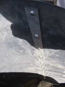 Bolts through metal strips holding overlapped ends of HDPE bamboo barrier