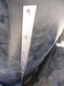 Bolts through metal strips holding overlapped ends of HDPE bamboo barrier