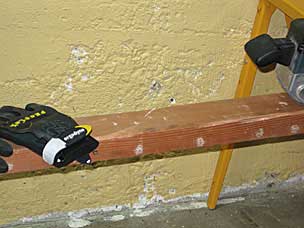 Preparing to sand faces of salvaged 2x4 with belt sander