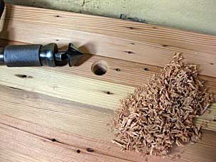 Chamfering rim of holdfast hole in workbench top