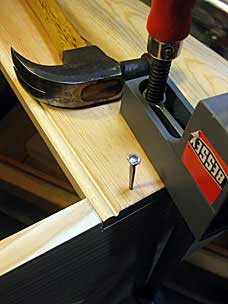 Driving rosehead cut nail into six board chest
